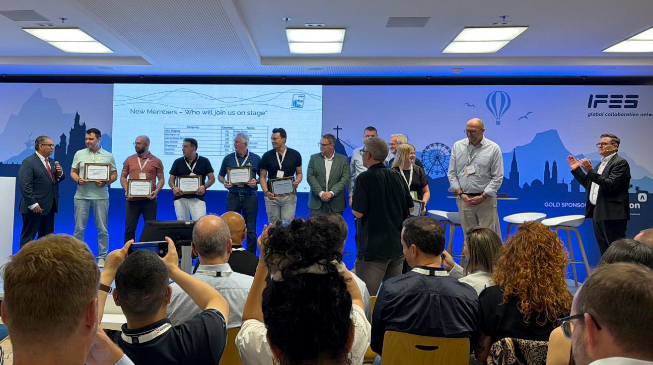 Offizielles Foto der Übergabe des IFES-Mitgliedszertifikats an die bee GmbH auf einer internationalen Messe.